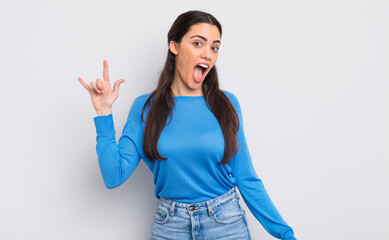 Wall Mural - pretty young woman feeling happy, fun, confident, positive and rebellious, making rock or heavy metal sign with hand