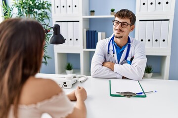 Canvas Print - Young doctor with client at medical clinic smiling looking to the side and staring away thinking.