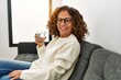 © Krakenimages.com - Middle age hispanic woman smiling confident drinking water at home