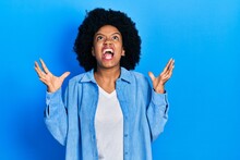 Young African American Woman Wearing Casual Clothes Crazy And Mad Shouting And Yelling With Aggressive Expression And Arms Raised. Frustration Concept.