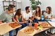 © Krakenimages.com - Group of young hispanic friends smiling happy eating italian pizza sitting on the sofa at home.