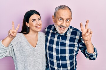 Sticker - Hispanic father and daughter wearing casual clothes smiling looking to the camera showing fingers doing victory sign. number two.