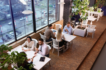 Canvas Print - Coworkers having coffee break near window in cafe, above view