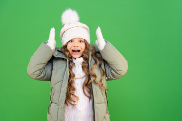 a child with a good mood in a winter jacket and hat. The little girl is glad of winter and warm clothes.  clothes for children in the cold season.
