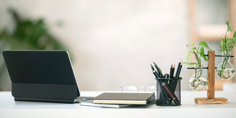 comfortable workspace with tablet and supplies on white top table in modern room.