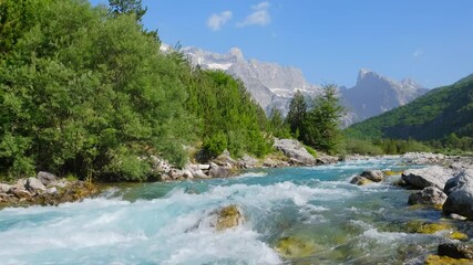 Wall Mural - Rapid mountain river water with majestic rocky mountains at background