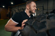 Strong energetic Caucasian sportsman performing tire exercise