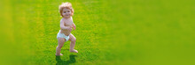 Banner With Spring Child Face. First Step. Baby Standing Barefoot On The Green Lawn In Diaper Pants. Kids On Green Grass Background.