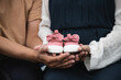 © krumanop - Close up, Pregnant women sit on bed with handsome husband and hold couple red baby shoes on the belly. A gift for the baby to be born in the future.