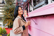 © Westend61 - Smiling woman with coffee cup near pink concession stand