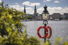 Germany, Hamburg, Life Belts Hanging On Street Light Standing On Shore Of Inner Alster Lake