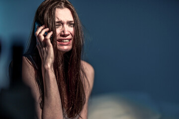 Wall Mural - Get the bad news. Broken heart. A woman with a face dirty from mascara sits in bed and cries, talking on the phone. To suffer. Heartbroken. Get upset. Depression