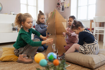 Wall Mural - Group of little girls painting cardboard tree at creative art and craft class at school