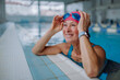 © Halfpoint - Happy senior woman in swimming pool, leaning on edge.
