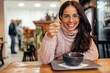 © bnenin - Smiling woman with glasses, eating at a restaurant and enjoying.