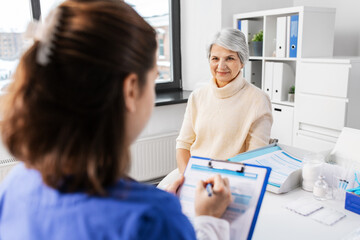 Sticker - medicine, health and vaccination concept - doctor with clipboard and senior woman at hospital