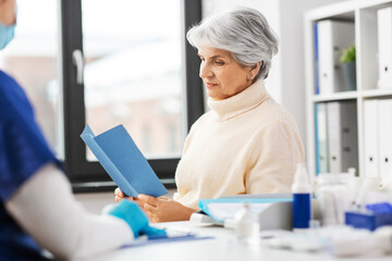 Poster - medicine, health and vaccination concept - doctor or nurse and senior woman reading medical brochure at hospital