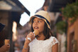 Cute Asian girl enjoying eating an ice cream in summer sunshine