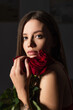© LIGHTFIELD STUDIOS - pretty young woman with bouquet of red roses looking at camera on dark background.