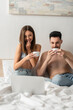 © LIGHTFIELD STUDIOS - happy and sexy couple drinking morning coffee while watching film on laptop in bedroom.