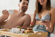 © LIGHTFIELD STUDIOS - selective focus of tray with pancakes and coffee near sexy young couple smiling on blurred background.