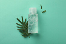 Bottle Of Cosmetic Gel And Leaves On Turquoise   Background, Flat Lay