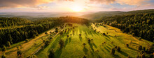 Aerial Landscape Panorama After Sunrise: Gorgeous Scenery With The Sun, Trees On Meadows In Warm Light Casting Long Shadows, Surrounded By Forests