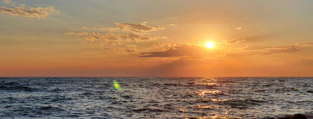 Wall Mural - colorful sunset with large sun under the sea waves.