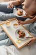 © LIGHTFIELD STUDIOS - cropped view of young couple eating delicious pancakes with fresh strawberries for breakfast in bedroom.