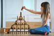Creative child girl playing with game stacking wooden toy blocks in high building structure. Hand movement control and concentration skills concept