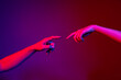 Two human hands trying to touch each other isolated on purple background in neon light. Concept of human relation, community, togetherness, symbolism, culture and history