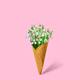 Fototapeta Tulipany - Flower ice cream. Snowdrops in a waffle cup on a pink background. Idea for March 8 or business