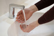 © Dzmitry - Photo of a man in a sweater who washes his hands under water in a white sink. Cleanliness and hygiene