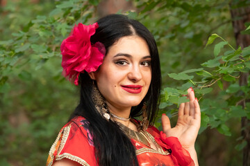 Gypsy woman. Red long dress. Portrait of a girl in an ethnic costume in the forest. The gypsy brunette is beautiful.