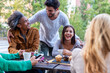 © MandriaPix - group of friends having fun during breakfast, people of different ethnic groups at the table of a pastry bar, students on break drinking coffee and cappuccino and eating muffins
