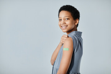 portrait of cute african-american girl showing shoulder patch and smiling at camera after getting va
