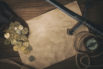 Travel or adventure flat lay background with copy space. Ancient gold coins,compass,rope and dagger on the old table.