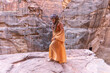 woman dressed in traditional clothes and headscarf staying at the top of rock on the background is Petra palace Jordan