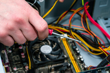 Wall Mural - a master with a screwdriver in his hand repairs an old dusty computer