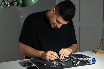 Sticker - Technician repairing broken smartphone at table indoors