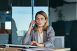 © Liubomir - Serious and anxious business woman talking on the phone, working in a modern office at the computer, close-up photo of a business conversation