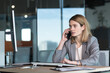 © Liubomir - Serious and anxious business woman talking on the phone, working in a modern office at the computer, close-up photo of a business conversation