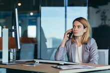 Serious And Anxious Business Woman Talking On The Phone, Working In A Modern Office At The Computer, Close-up Photo Of A Business Conversation