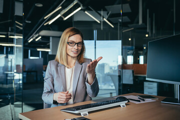 Video call of a happy and successful business woman, an employee has an online meeting, advises employees, looks at the webcam and cheerfully explains gesturing with her hands