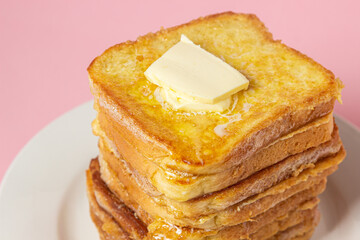 Wall Mural - eggy bread on a pink background. Butter melts on a stack of eggy breads. Tasty breakfast.