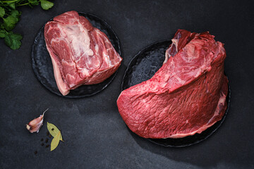 Wall Mural - Fresh cut of beef on a black plates with spices. Raw steak beef meat  and pig  fillet ready to cook. Selective focus