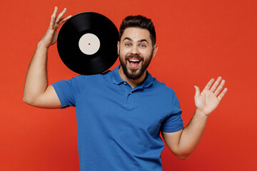 Wall Mural - Young excited happy satisfied cheerful fun man 20s wear basic blue t-shirt looking camera hold retro vintage music plate isolated on plain orange background studio portrait. People lifestyle concept.