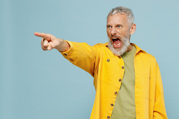 Wall Mural - Elderly angry strict indignant gray-haired mustache bearded man 50s wear yellow shirt point index finger aside scream isolated on plain pastel light blue background studio. People lifestyle concept.