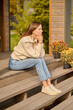 © zinkevych - Woman sitting on porch of house sideways to camera