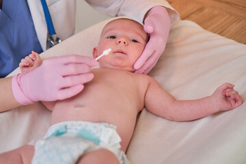the doctor performs the hygiene of the nose and ears of the newborn baby with a cotton swab. nurse i